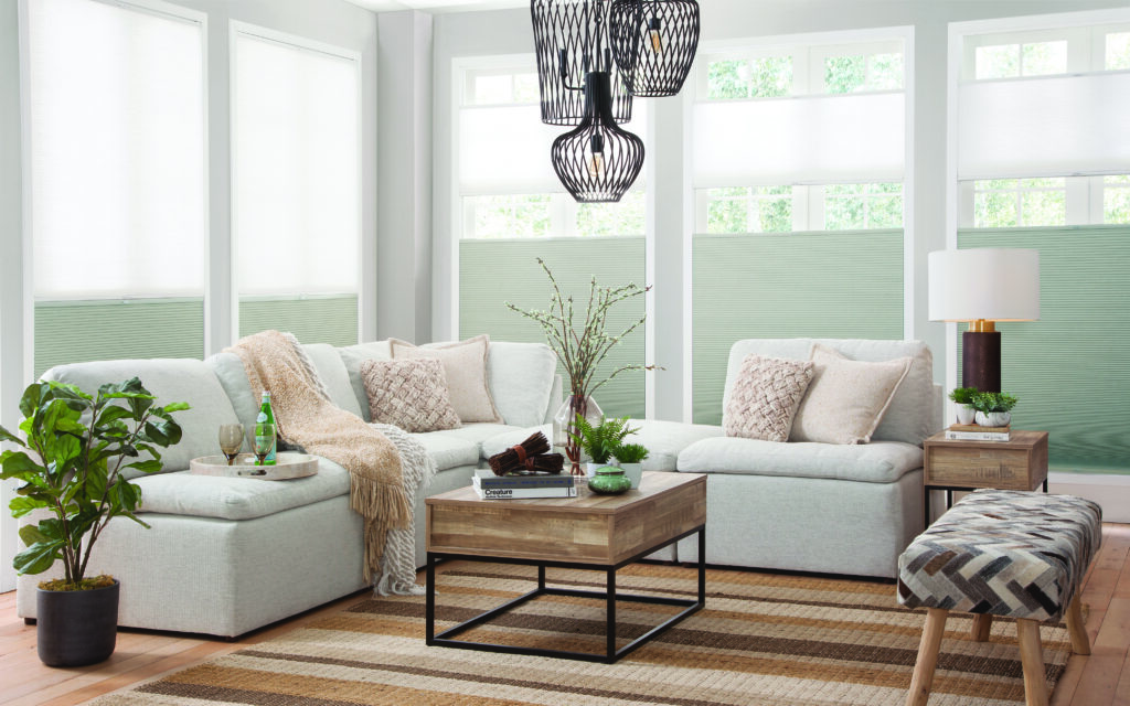 a living room with custom cellular shade window treatments. a couch and a coffee table.